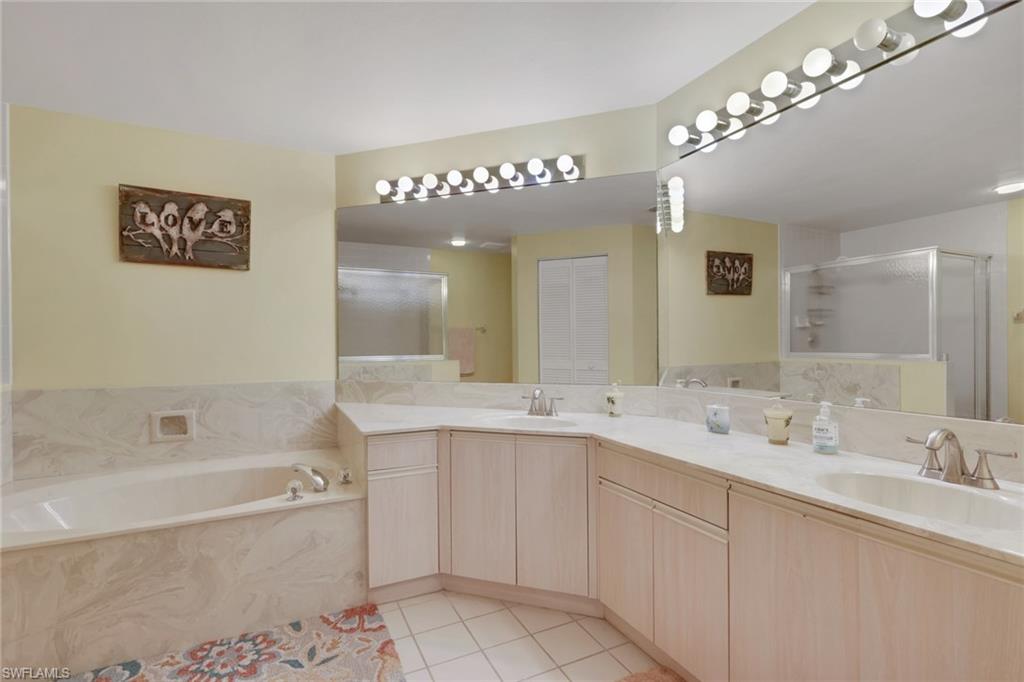 6260 Bellerive Avenue, Unit 4 Naples, FL 34119 - Photo 16 of 27 a bathroom with a tub a double vanity sink and a mirror