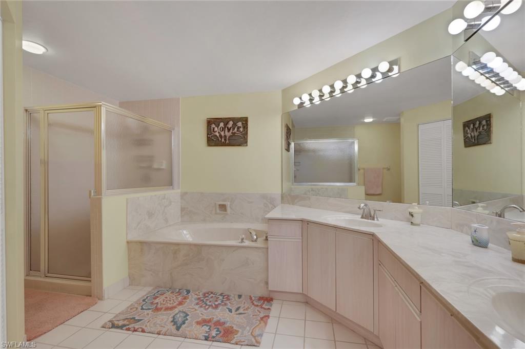 6260 Bellerive Avenue, Unit 4 Naples, FL 34119 - Photo 17 of 27 a bathroom with a sink a large mirror and a shower