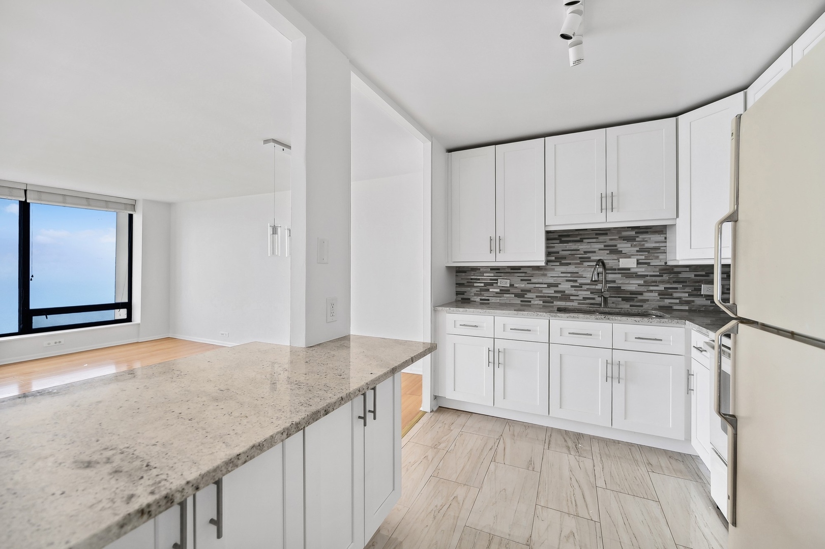 5445 North Sheridan Road, Unit 3104 Chicago, IL 60640 - Photo 8 of 15 a kitchen with granite countertop white cabinets and white appliances