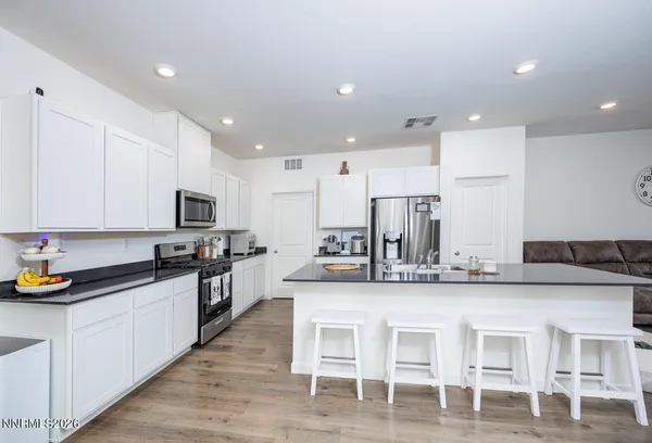 a kitchen with stainless steel appliances granite countertop a stove top oven a sink and white cabinets