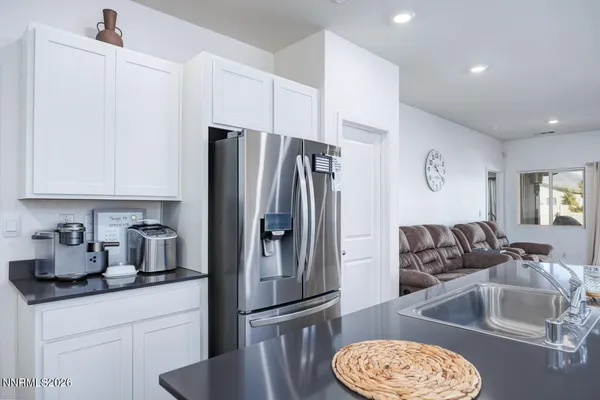 a kitchen with granite countertop a refrigerator a sink and white cabinets