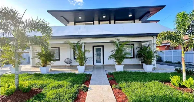 a front view of a house with garden and plants