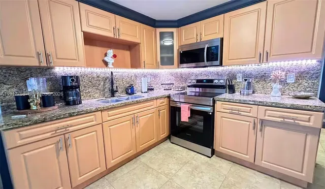 a kitchen with granite countertop white cabinets sink and stainless steel appliances