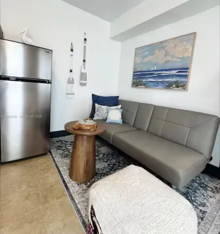 a living room with furniture and a refrigerator