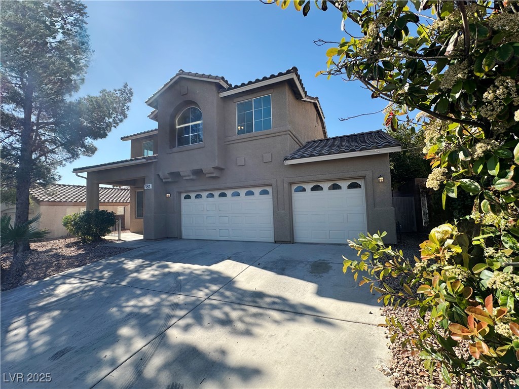 181 Ruby Ridge Avenue Henderson, NV 89002 - Photo 3 of 44 View of front facade featuring a garage, a tile roof, stucco siding, and driveway
