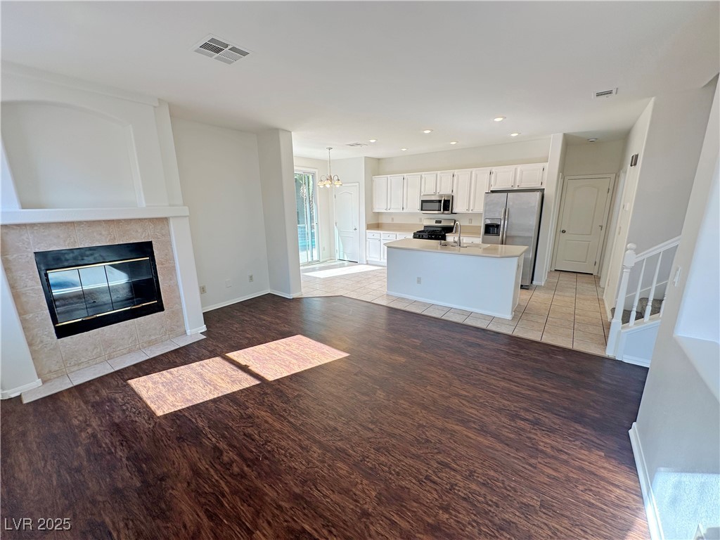 181 Ruby Ridge Avenue Henderson, NV 89002 - Photo 7 of 44 Unfurnished living room with a fireplace, a chandelier, light wood finished floors, recessed lighting, and stairway