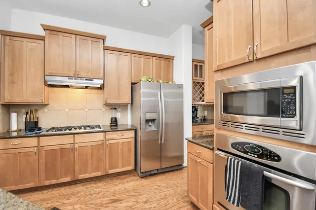 a kitchen with stainless steel appliances granite countertop a refrigerator a stove and a sink