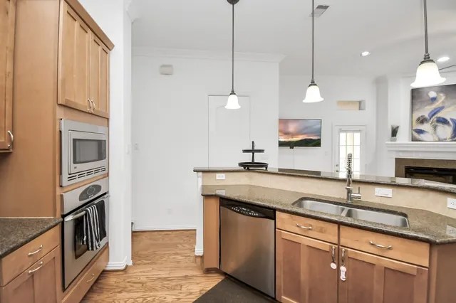 a kitchen with stainless steel appliances granite countertop a sink a stove and a wooden floors