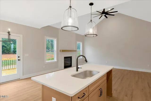 a kitchen with a sink a chandelier stainless steel appliances and cabinets