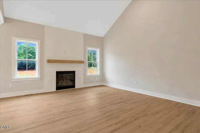 a view of empty room with wooden floor and fireplace