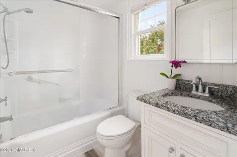 a bathroom with a granite countertop sink toilet and shower