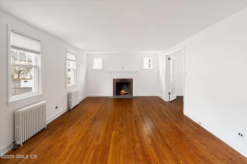 an empty room with wooden floor fireplace and windows