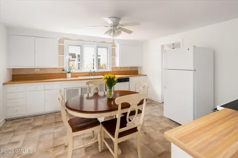 a dining room with stainless steel appliances kitchen island granite countertop a table chairs and a refrigerator