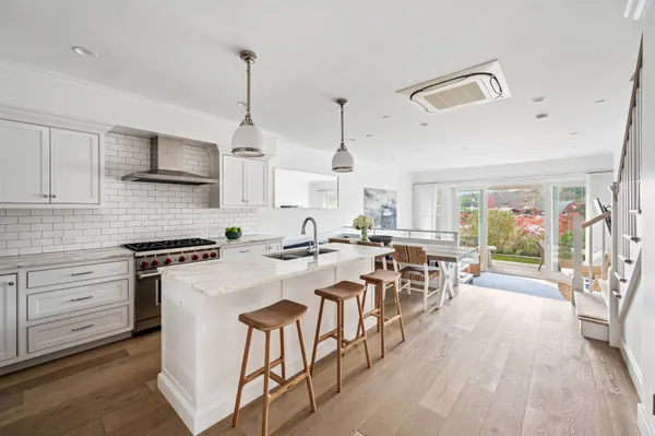 a kitchen with stove a sink dishwasher a dining table and chairs with wooden floor