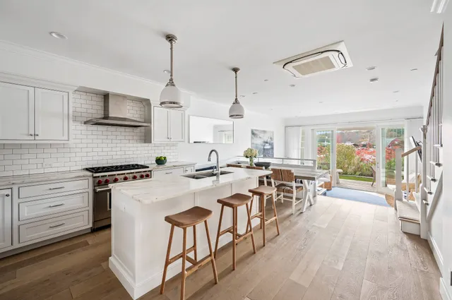 a kitchen with stove a sink dishwasher a dining table and chairs with wooden floor