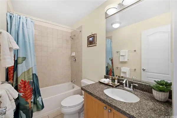 a bathroom with a granite countertop sink a toilet a tub and shower