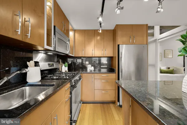 a kitchen with stainless steel appliances granite countertop a sink a stove and a refrigerator