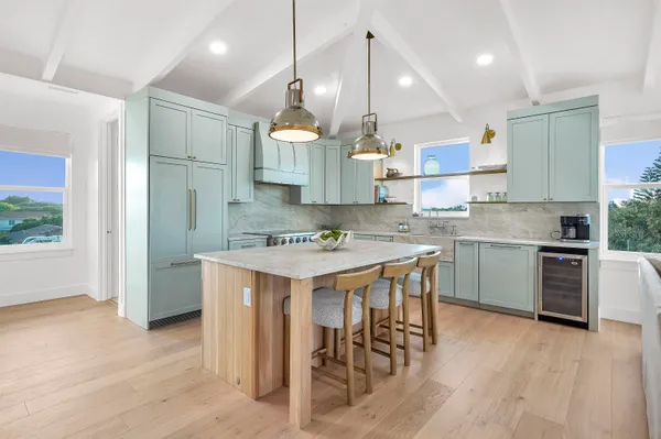 a kitchen with kitchen island granite countertop a sink a stove a refrigerator and island with wooden floor