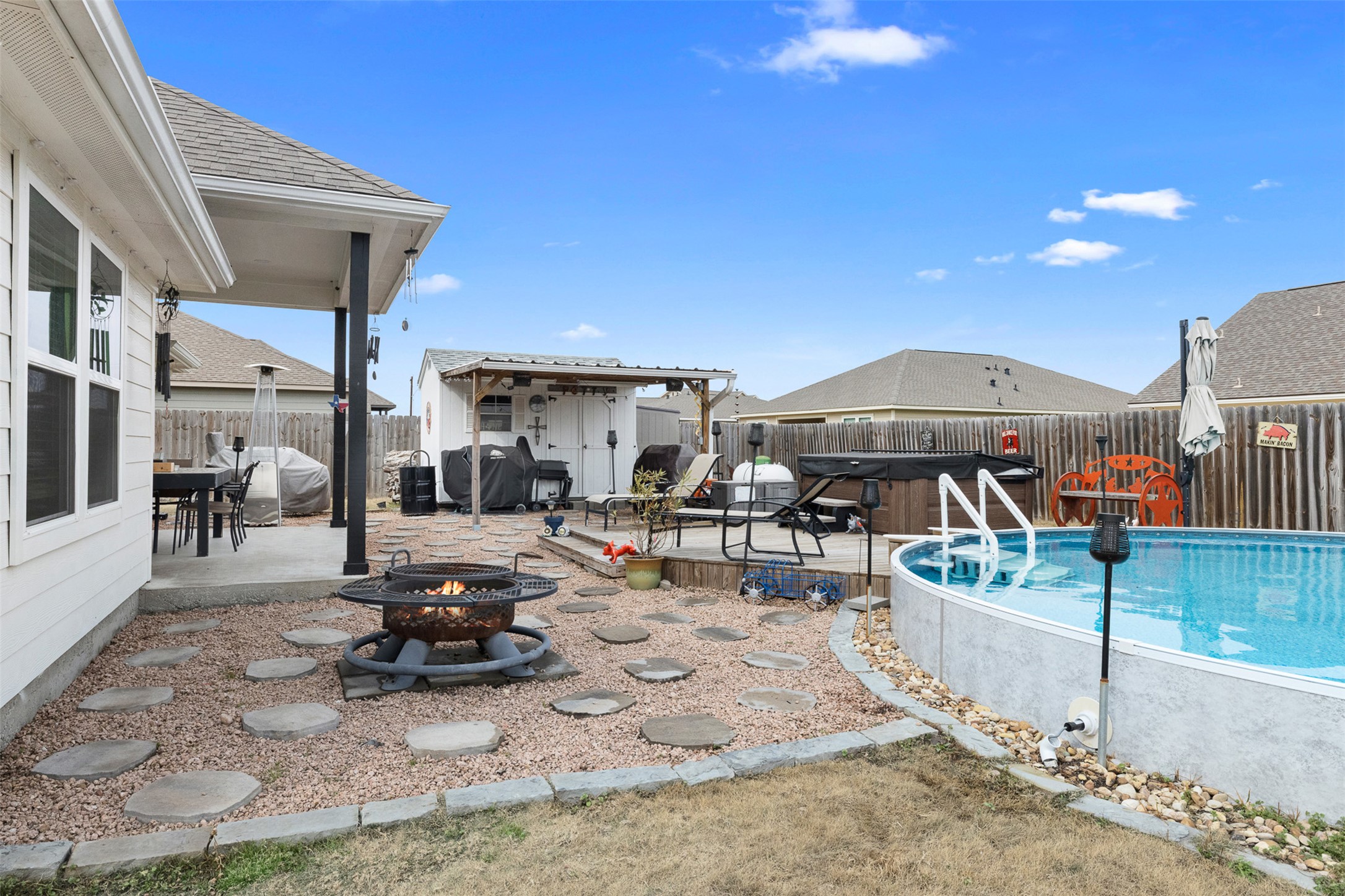 149 Windmill Road Somerville, TX 77879 - Photo 8 of 31 View of swimming pool featuring a hot tub, an outdoor fire pit, patio surround, a fenced backyard, and area for grilling