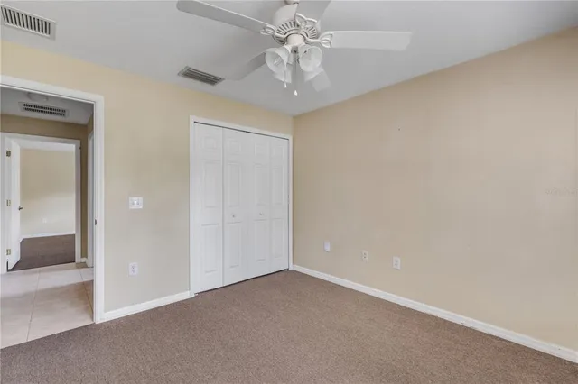 a view of an empty room and chandelier fan