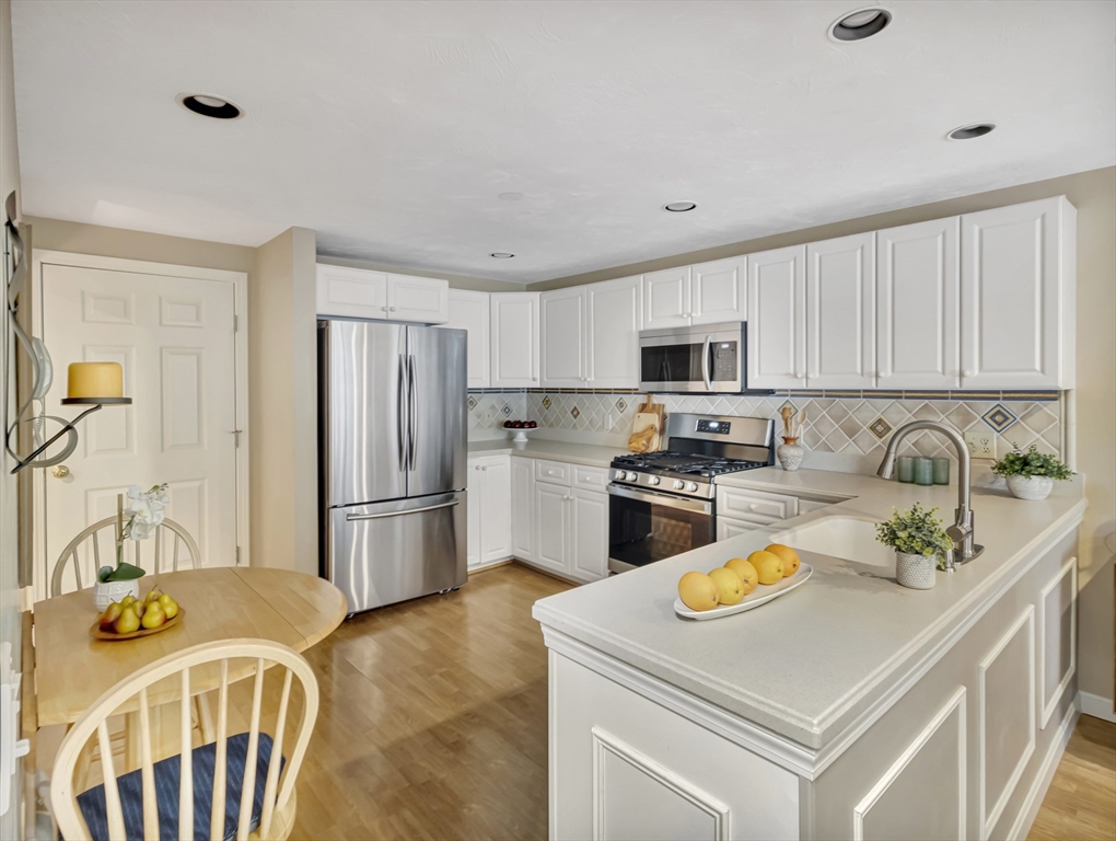 10 Kettle Lane, Unit 10 Mashpee, MA 02649 - Photo 7 of 25 a kitchen with stainless steel appliances granite countertop a sink a stove a refrigerator a stove a oven with a dining table and chairs