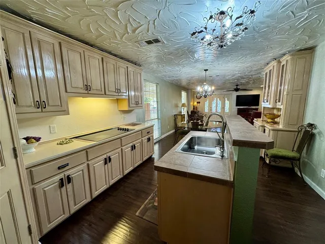 a kitchen with stainless steel appliances kitchen island granite countertop a sink dishwasher stove and wooden cabinets