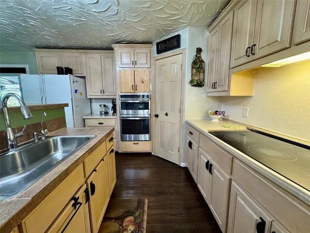 a kitchen with stainless steel appliances a sink dishwasher a refrigerator a stove top oven a refrigerator and cabinets