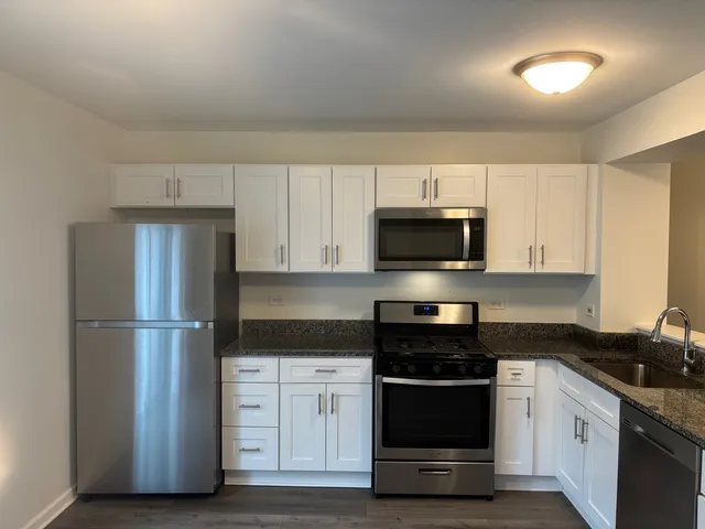 a kitchen with granite countertop a refrigerator and a stove top oven