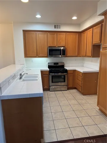 a kitchen with stainless steel appliances a sink a stove top oven a counter space and cabinets