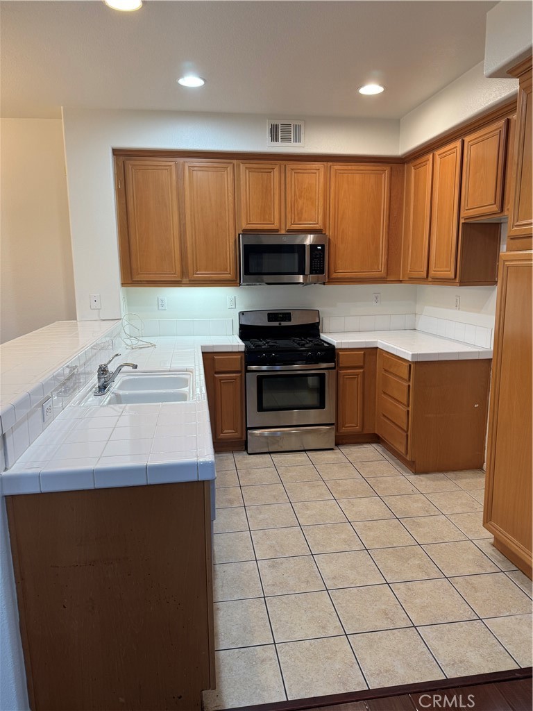 12268 Chantrelle Drive Rancho Cucamonga, CA 91739 - Photo 4 of 12 a kitchen with stainless steel appliances a sink a stove top oven a counter space and cabinets