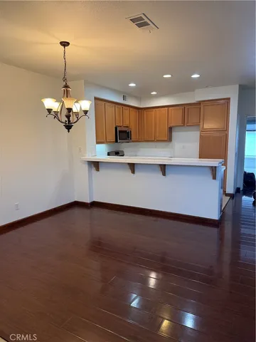 a view of a kitchen with kitchen island a sink wooden floor and a chandelier