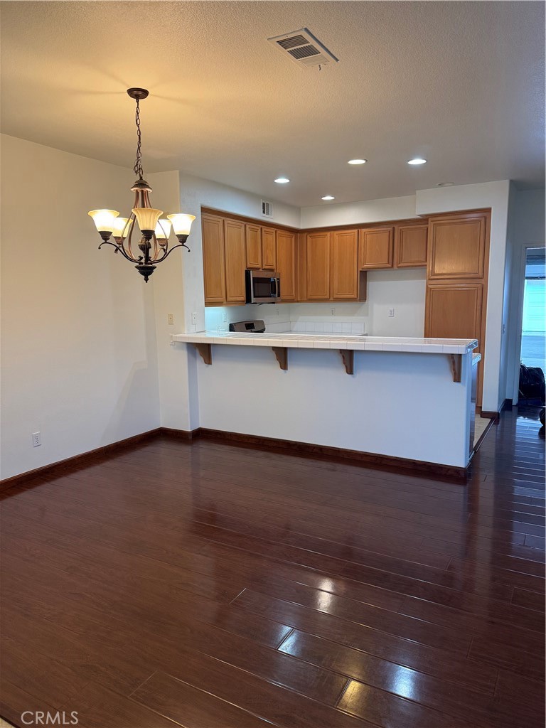 12268 Chantrelle Drive Rancho Cucamonga, CA 91739 - Photo 5 of 12 a view of a kitchen with kitchen island a sink wooden floor and a chandelier