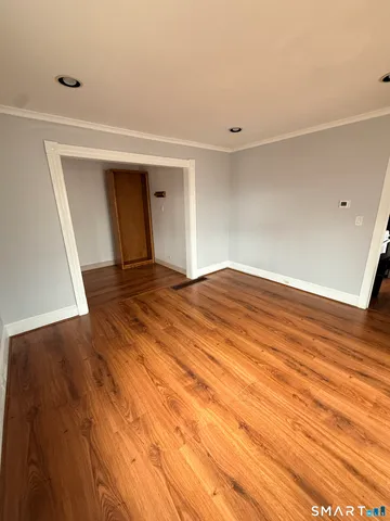 a view of an empty room with wooden floor and closet