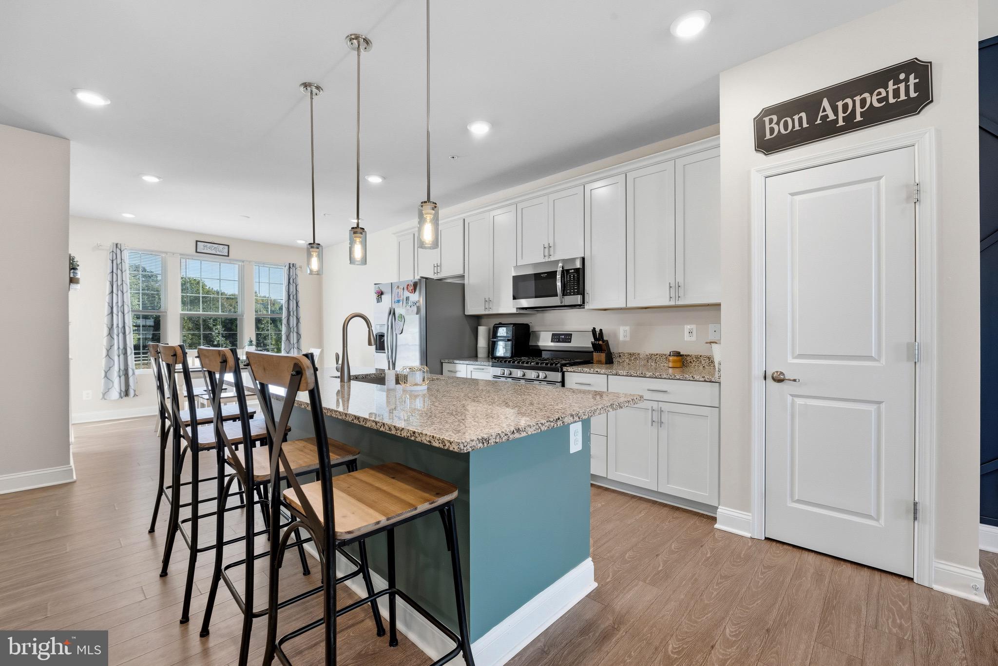 403 Dryden Road Aberdeen, MD 21001 - Photo 5 of 44 a kitchen with stainless steel appliances granite countertop a stove a sink a microwave a refrigerator a dining table and chairs with wooden floor