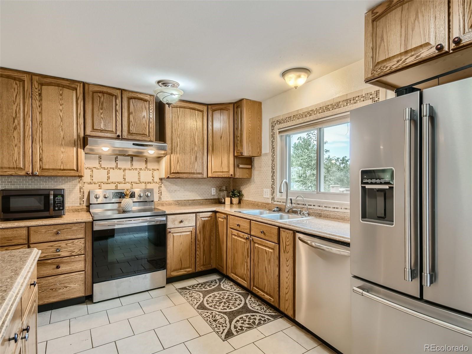 11111 Hudson Place Thornton, CO 80233 - Photo 12 of 28 a kitchen with stainless steel appliances granite countertop a refrigerator and wooden cabinets