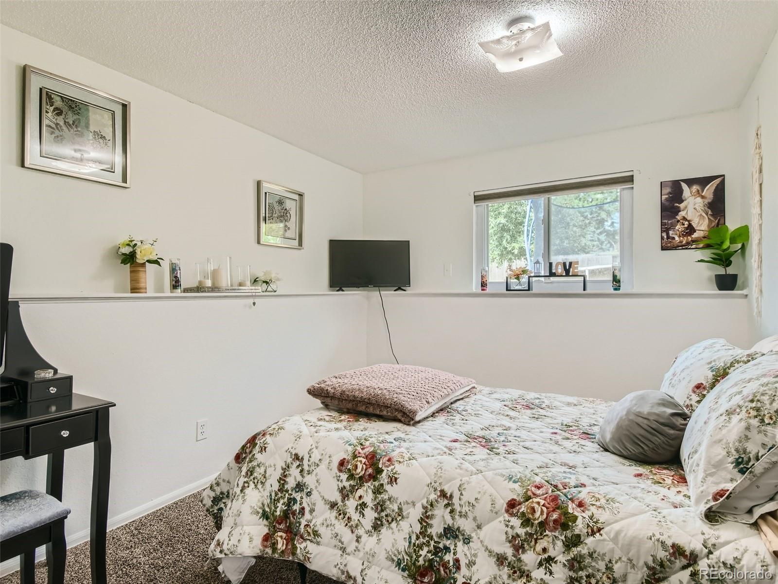 11111 Hudson Place Thornton, CO 80233 - Photo 20 of 28 a bedroom with a bed and a flat screen tv