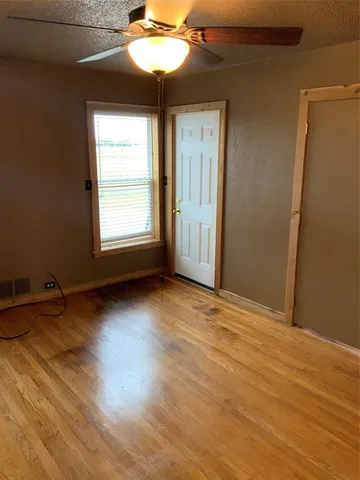 an empty room with windows and chandelier fan