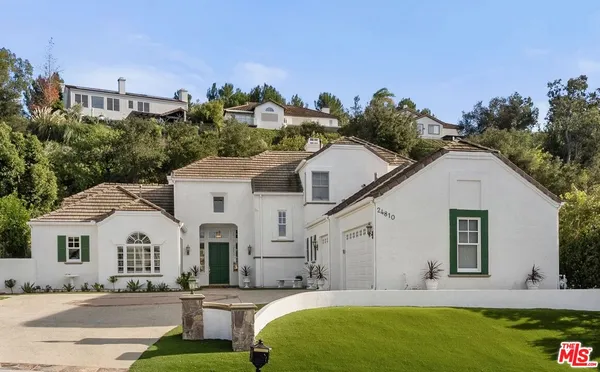 a view of a white house with a big yard and potted plants
