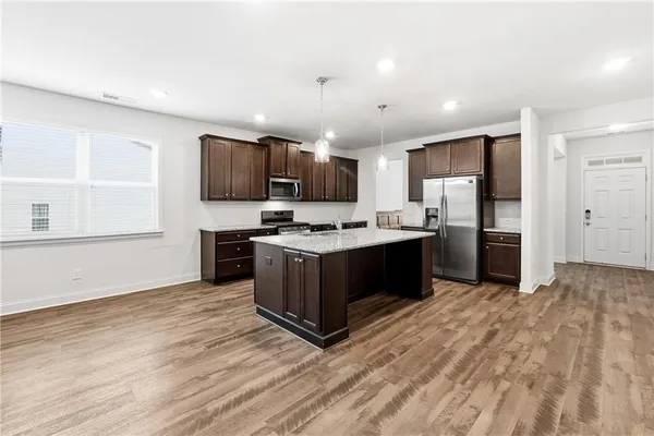 a large kitchen with a center island wooden floor stainless steel appliances and a window