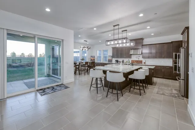 a dining room with stainless steel appliances kitchen island granite countertop a dining table chairs and a refrigerator