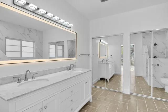 a bathroom with a granite countertop double vanity sink mirror and shower
