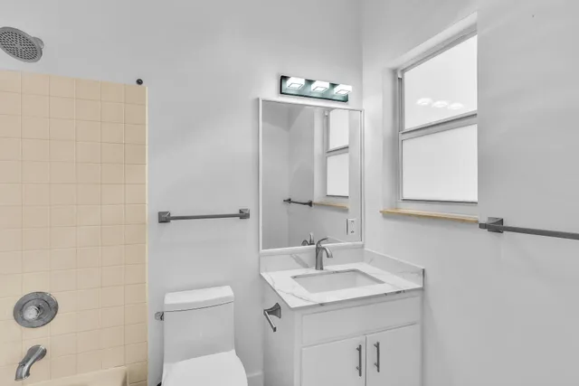a bathroom with a granite countertop sink toilet and mirror