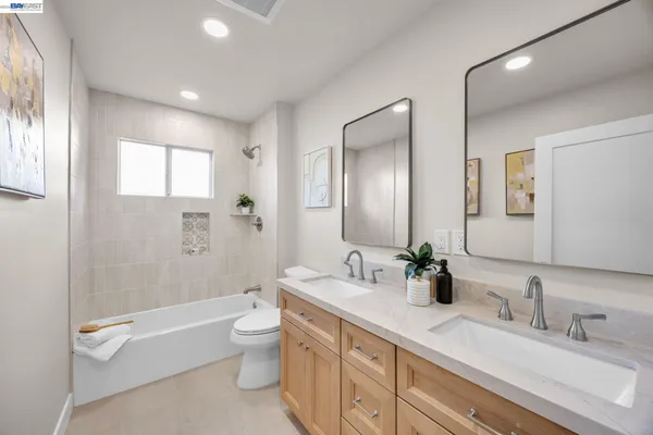 a spacious bathroom with a double vanity sink toilet mirror and shower