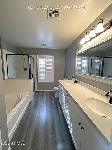 a bathroom with a granite countertop double vanity sink a mirror and a bathtub