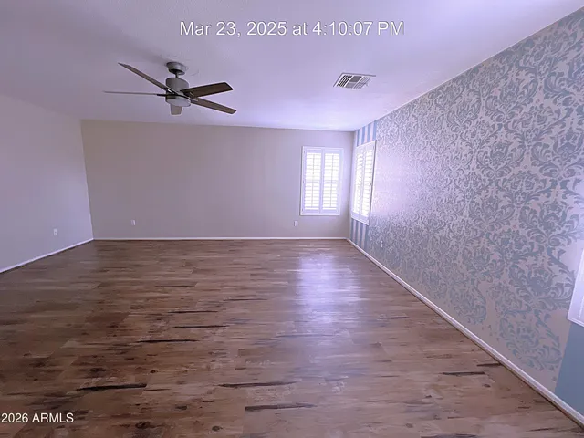 a view of a room with wooden floor and a ceiling fan