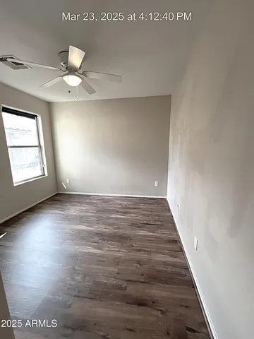 an empty room with wooden floor chandelier fan and windows