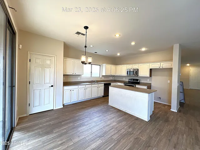 a large kitchen with a center island wooden floor and stainless steel appliances