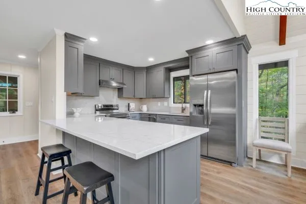 a large kitchen with kitchen island a large counter top space a sink stainless steel appliances and cabinets