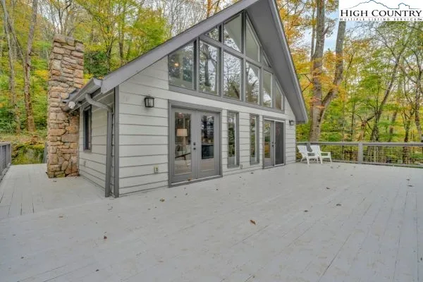 a view of a house with a wooden deck and a small yard