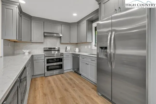 a kitchen with stainless steel appliances granite countertop a refrigerator a sink and a stove